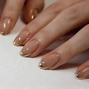 Macro view of almond press-on nails with nude base and gold chrome French tips