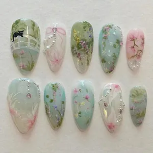 Close-up detail of artistic hand-painted press-on nails featuring floral and cat motifs