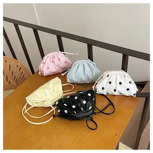 Close-up of pleated polka dot dumpling crossbody bags in pink blue black and white