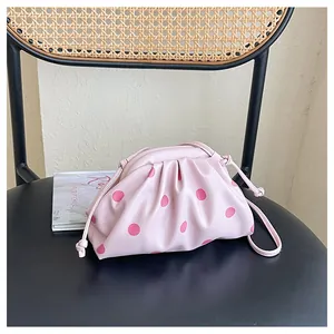 Detail view of pink polka dot pleated dumpling bag on a stylish woven chair