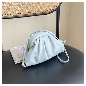 Close-up view of a light blue pleated dumpling bag with yellow polka dots on a chair.