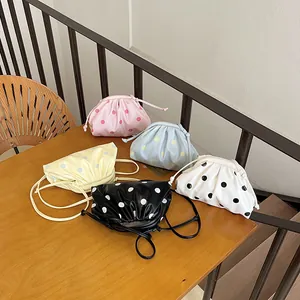 Trendy pleated polka dot dumpling bags in multiple colors shown on a wooden table