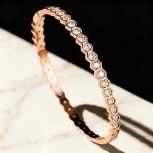 Close-up of rose gold hexagonal bangle with sparkling diamonds on marble background