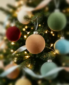 Close-up of luxury velvet flocked Christmas ball ornaments hanging on a lit tree.