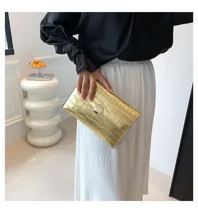 Elegant gold stone pattern envelope clutch bag shown in a lifestyle model shot