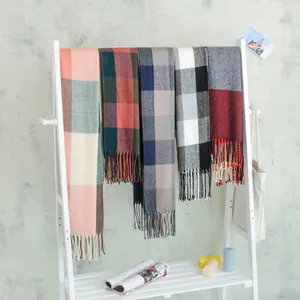 Collection of various plaid faux cashmere scarves with tassels on a display rack