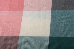 Close-up macro detail of soft imitation cashmere plaid shawl in pink and teal.
