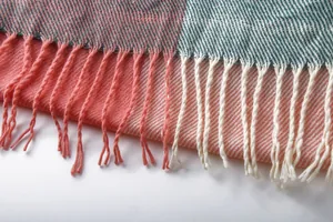 Detailed close-up view of a pink and green plaid scarf featuring soft fringe tassels
