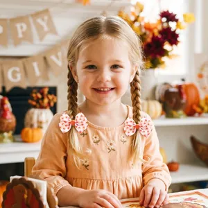 Barrettes à nœud imprimées pour filles portées sur des nattes dans un décor automnal festif