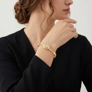 Detail shot of an elegant gold shell bangle with sparkling zircons worn on a model's wrist