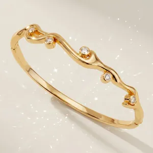 Élégant bracelet doré en forme de vague serti de zircons brillants et fermoir à charnière