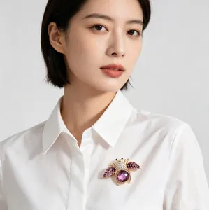 Gros plan d'une broche abeille en cristal violet sur une chemise blanche.