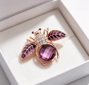 Détail d'une broche abeille en cristal violet avec strass dans un coffret cadeau blanc