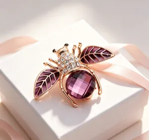 Détail d'une élégante broche abeille dorée avec une pierre violette et des strass