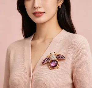 Vue détaillée d'une broche abeille en cristal violet avec ailes dorées sur un gilet rose