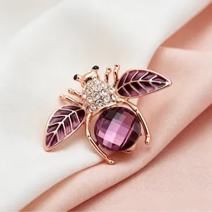 Sparkly purple bee brooch with crystal inlay and rose gold wings on silk background
