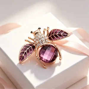 Elegant gold bee brooch with purple crystals and enamel wings presented on a white gift box