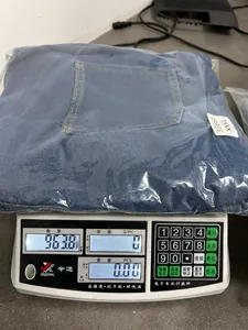 Detailed view of men's blue denim overalls being weighed on an electronic scale.