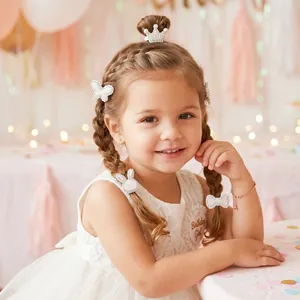 Petite fille portant des barrettes à perles et strass blancs pour anniversaire.