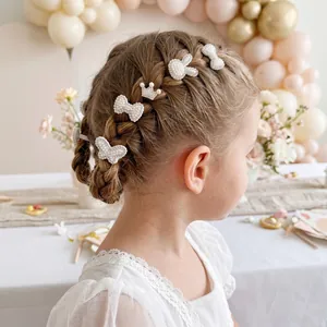 Vue détaillée de pinces à cheveux en perles blanches et strass sur des cheveux tressés.