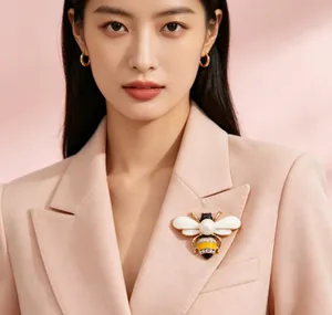 Detailed view of an elegant honeybee brooch with pearl and rhinestones on a pink blazer.