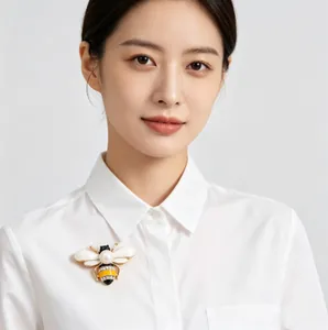 Close-up of elegant bee brooch with pearl and rhinestones on white shirt