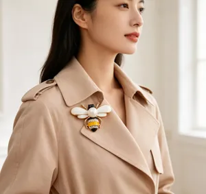 Close-up of pearl bee brooch with rhinestones on beige trench coat collar