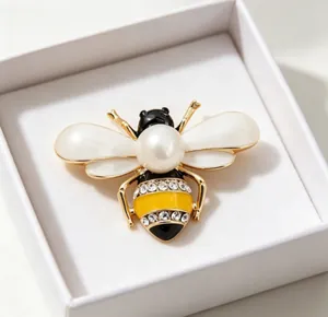 Detailed macro view of an elegant bee brooch with white enamel wings and a center pearl