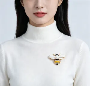 Detailed view of an elegant bee brooch with pearl and crystals on a sweater