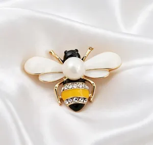 Macro view of gold-toned honeybee brooch featuring white pearl and sparkling rhinestones