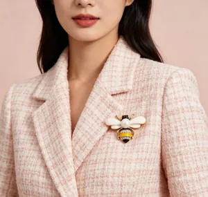 Detailed view of an elegant bee brooch with pearl and rhinestones on a pink tweed jacket