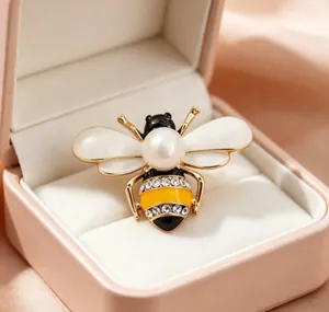 Macro detail of a bee brooch with a large pearl and sparkling rhinestone stripes
