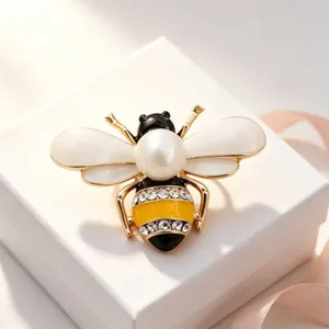 Elegant gold-tone bee brooch featuring a large pearl and sparkling rhinestone details