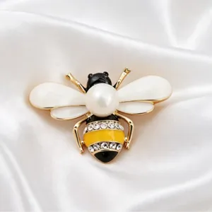 Elegant enamel bee brooch with pearl and rhinestone accents on white satin