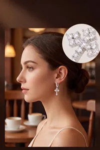 Detail view of zircon cross earrings worn by a model in an elegant cafe setting