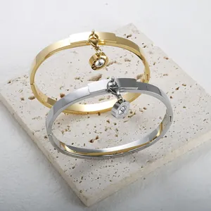 Elegant gold and silver bangles with Roman numeral charms and crystals on stone background