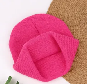 Detailed close-up of a vibrant hot pink knitted beanie hat showing fine ribbed texture.
