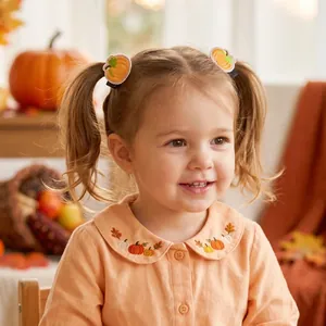 Cute Thanksgiving pumpkin embroidered hair clips for baby girls on toddler model.