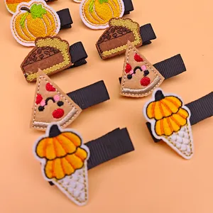 Detailed view of Thanksgiving embroidered hair clips with pumpkin and food patterns