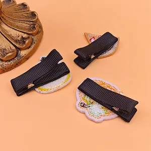 Detail showing the back of safety embroidered hair clips with black fabric-wrapped clips.