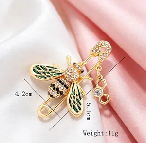 Detail shot of a gold-toned bee brooch with green enamel wings and rhinestones