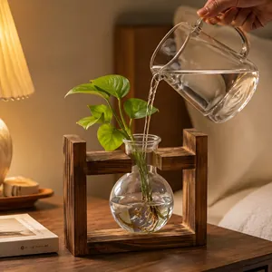 Detail showing water being poured into a hydroponic bulb vase on a rustic wood stand.