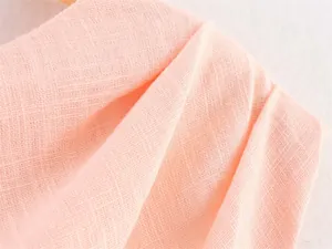 Close-up of soft peach woven fabric detail for asymmetrical midi dress