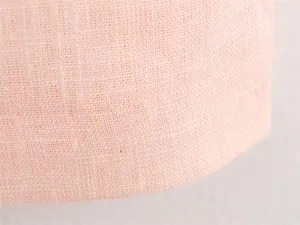Macro detail view of the light pink linen-like fabric texture of the midi dress.