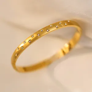 Close-up of gold titanium steel starry bangle with small star-shaped crystals.