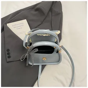 Detailed view of a light blue crossbody bag with checkered bow and lace trim