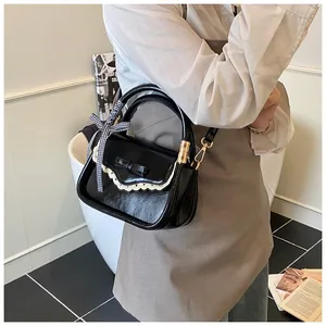 Detailed view of black handbag with lace trim, bow detail, and checkered ribbon.