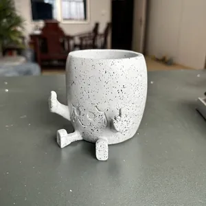 Close-up of gray speckled resin planter with middle finger gesture and smiley face.