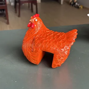 Close-up detail of a bright orange resin hen ornament for garden fence decoration.