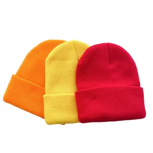 Close-up of three solid color knitted beanie hats in candy colors orange yellow and red